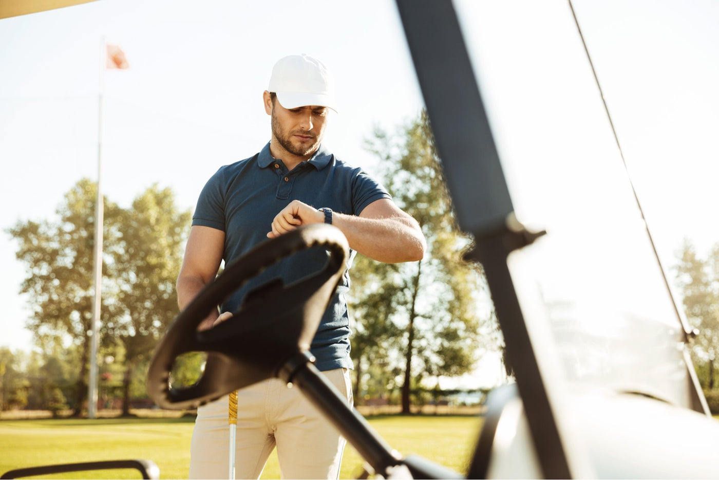 golfer looking at watch near golf cart